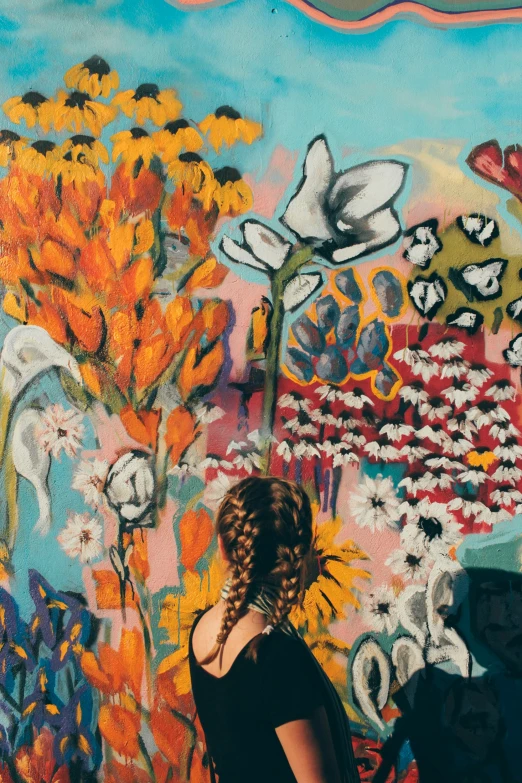 the person is standing near a mural with flowers