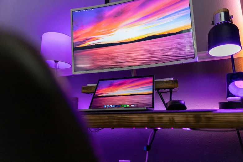 a couple computers sit on a wooden desk