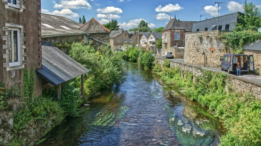 a river runs through an old town with a building line and trees