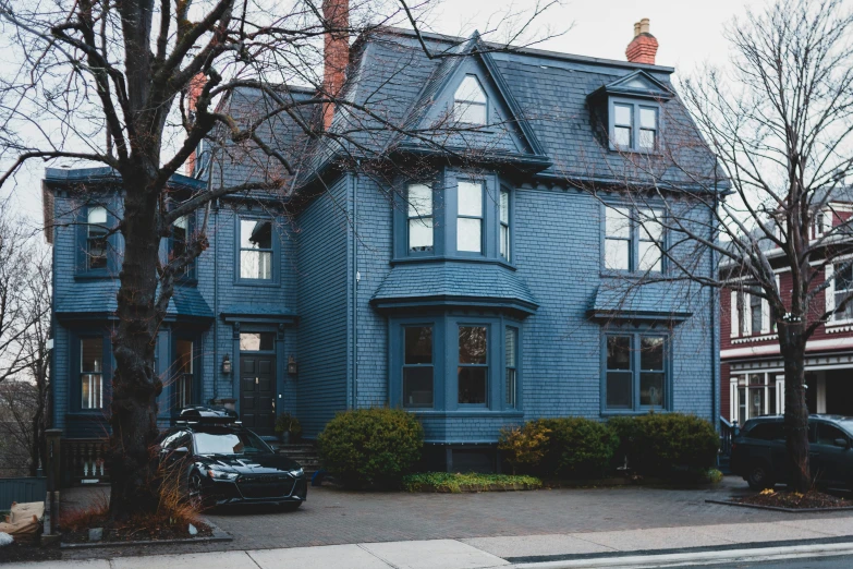 an blue two story house next to some trees