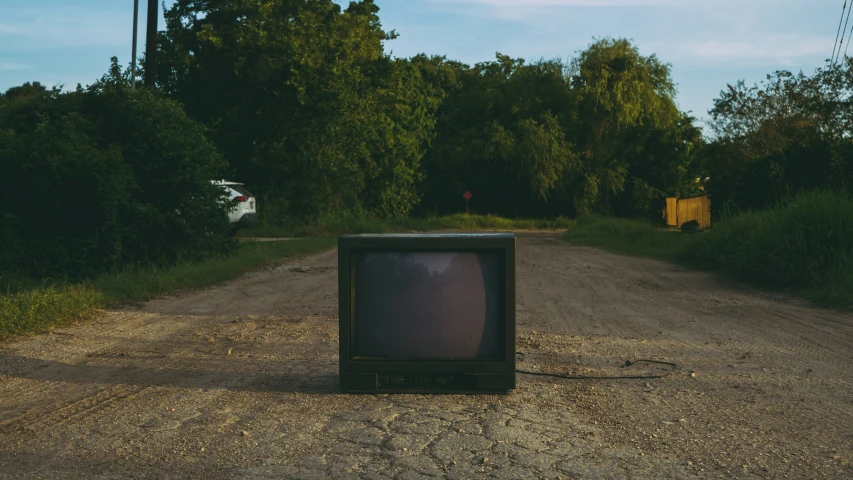 an old tv sitting on the side of the road