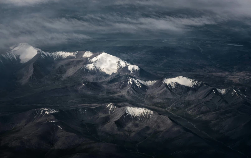 a pograph taken from an airplane of mountains with snow