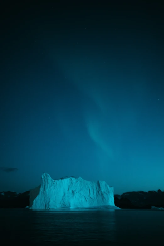 an iceberg floating in the ocean at night
