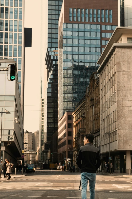 man standing at the end of a street with traffic lights