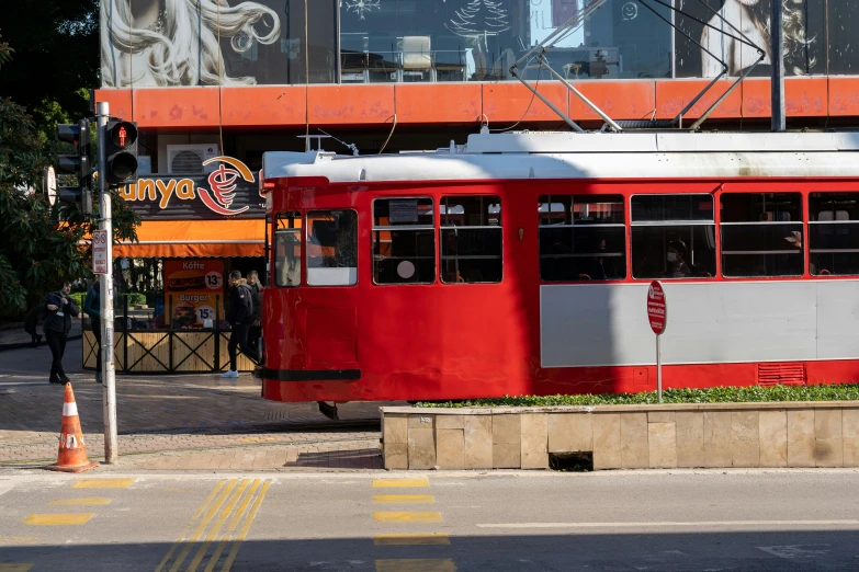 red, white and black trolley on city street next to a building