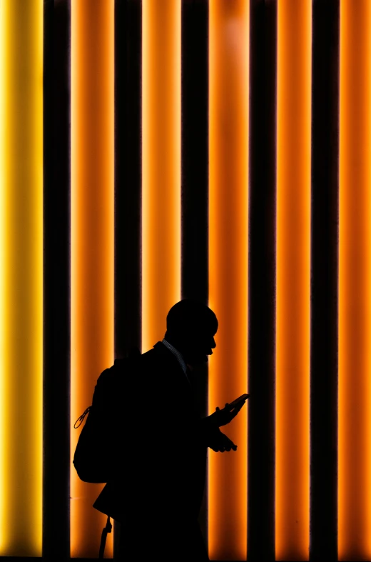 the man is standing in front of the wall using his phone