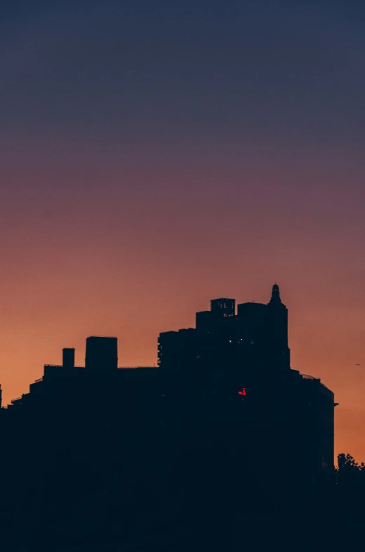 silhouette of a city at dusk with the moon rising above