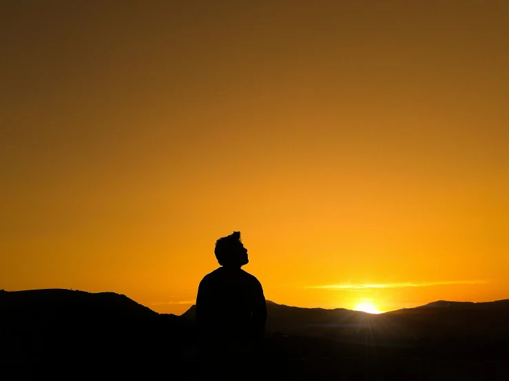 a person with a backpack looking at the sunset