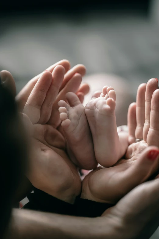 a woman holds out her baby's hands as it lays on its back