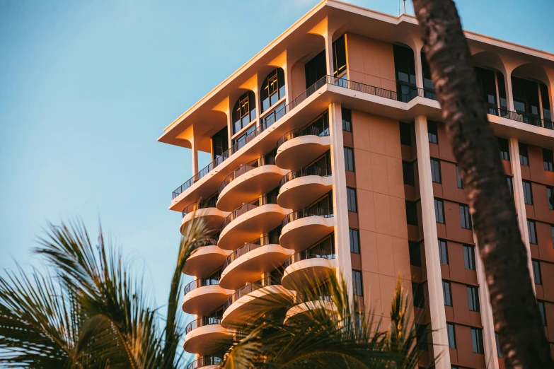 an apartment building next to palm trees on the side of the street