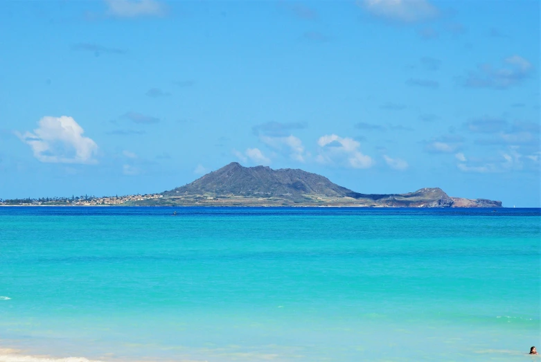 two people are on the beach with the ocean and mountains in the background