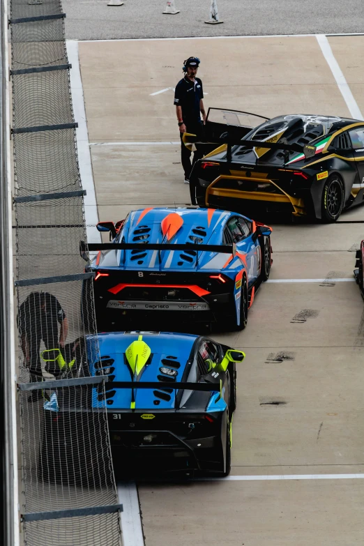 a person standing by a few cars on a track