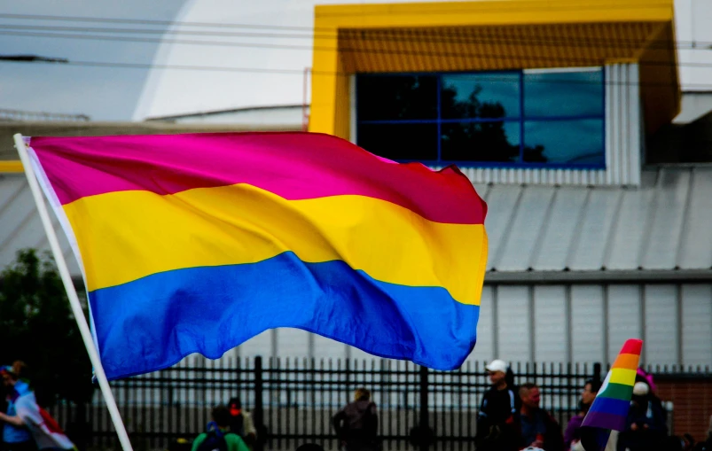 the rainbow flag flies in front of a group of people walking