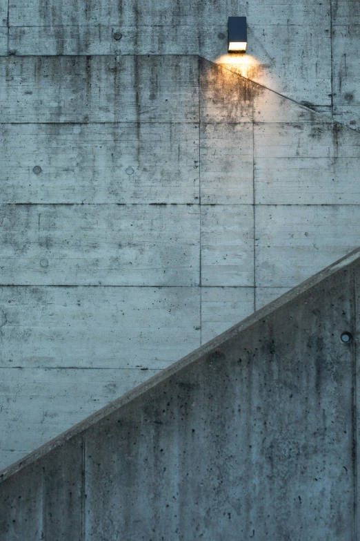 a concrete stairway with a concrete wall and lamp