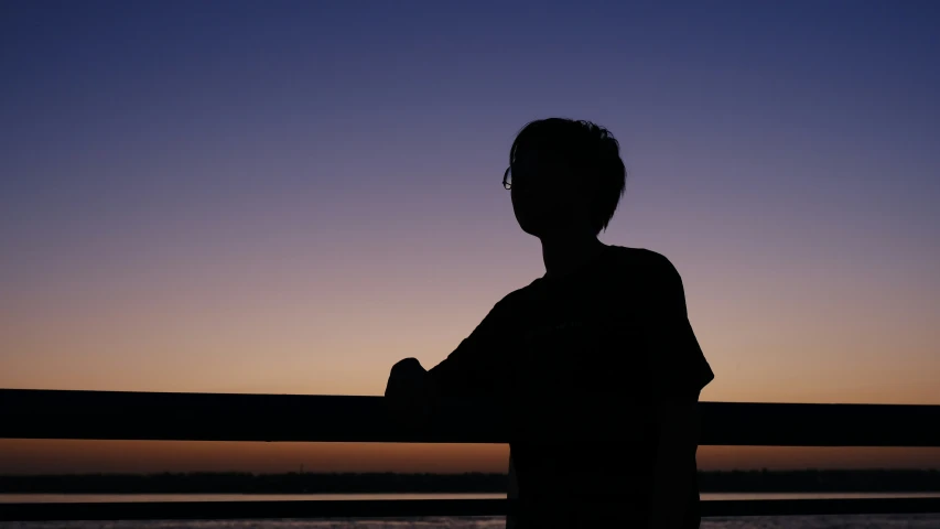 silhouette of person standing in front of ocean during twilight