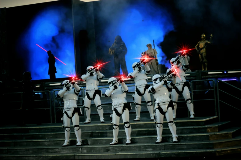 several actors in white costumes on stage with lights behind them