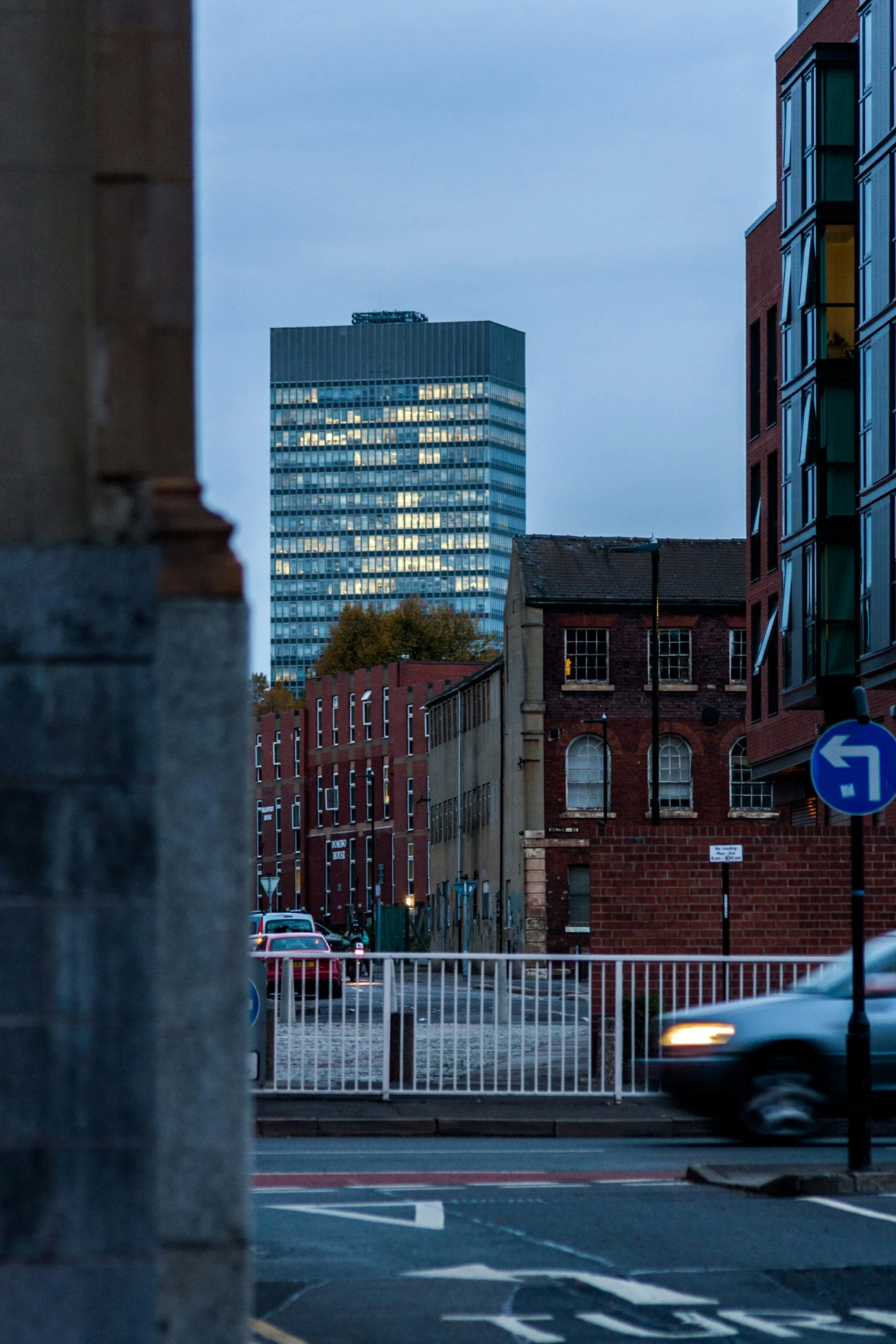 a building at dusk in the distance with cars passing by on it