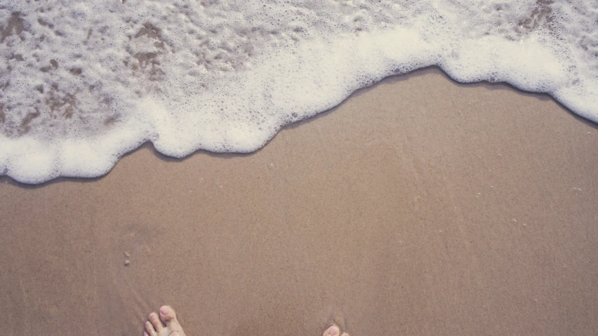 a person's feet that are standing in the sand