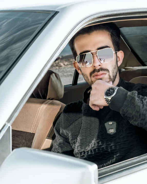 man in glasses sitting inside his car wearing a watch