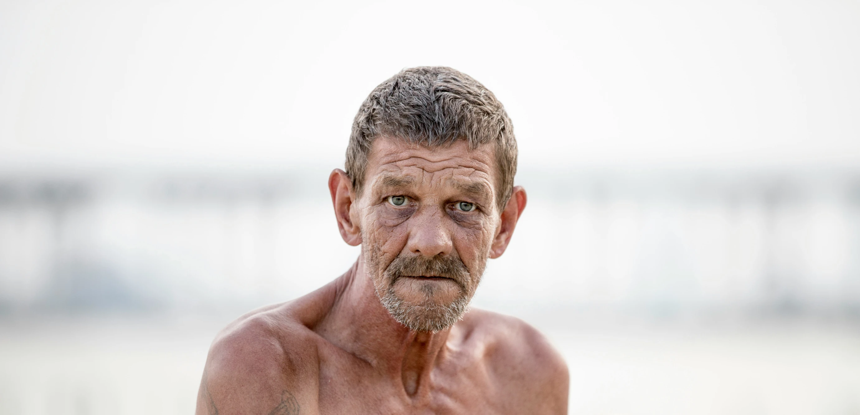 an older man standing on the beach looking ahead