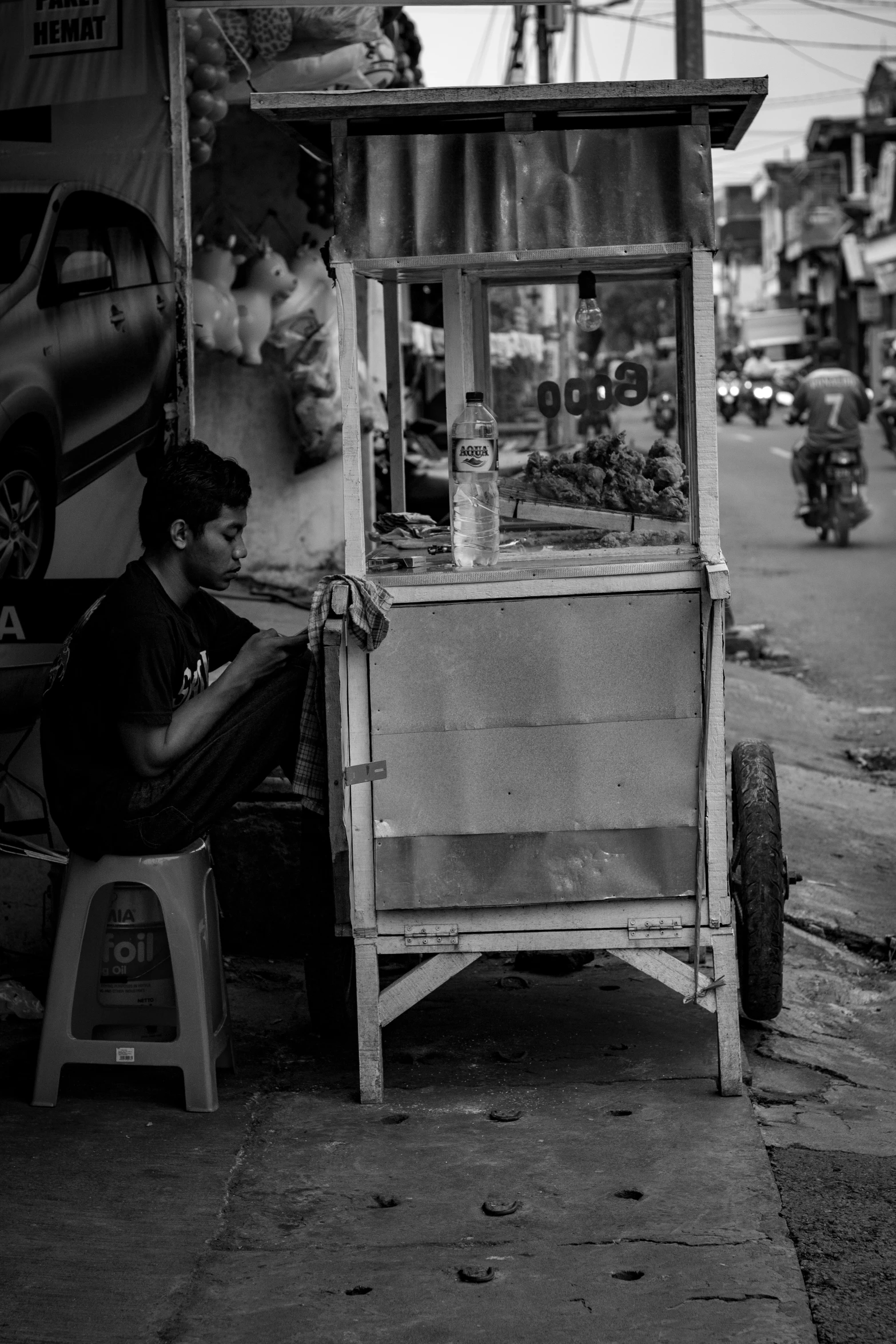 man at a fruit stand sitting on a side walk