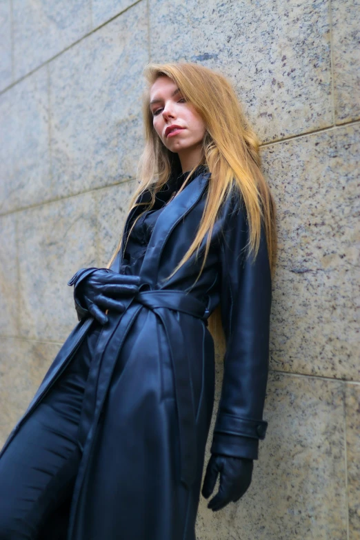 a woman wearing black is leaning on the side of a wall