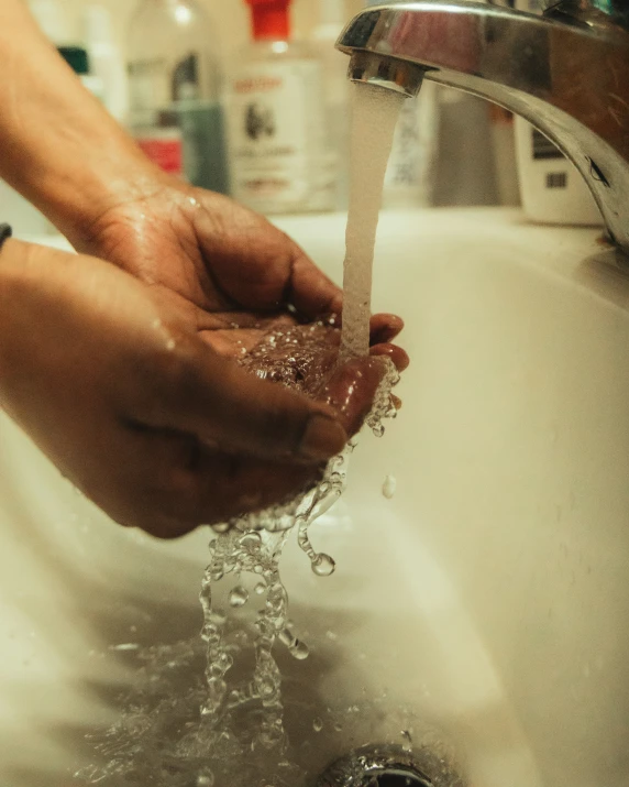 person washing their hands in the sink with running water