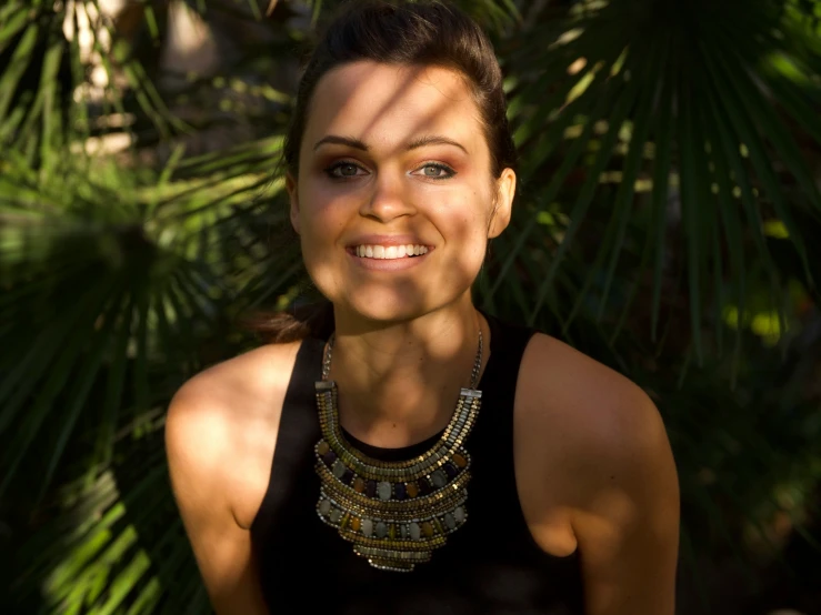 a woman is smiling in front of some leaves