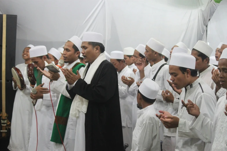 a group of men wearing white outfits with green accents holding hands together