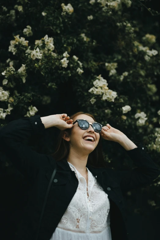 a woman in glasses standing with her hands on her ears