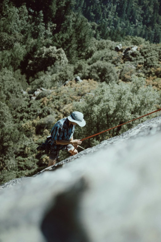 person climbing uphill with hat on a mountain