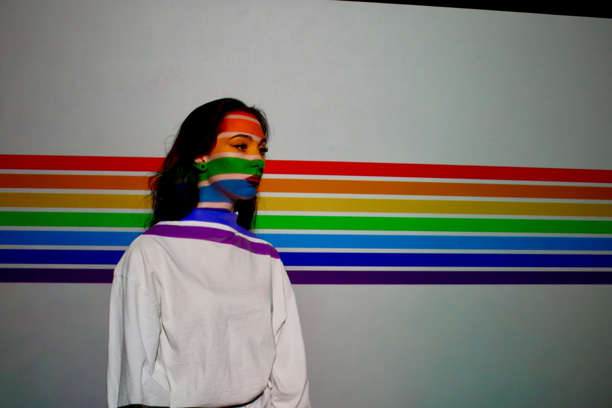 a woman has her face painted green, yellow, blue and orange