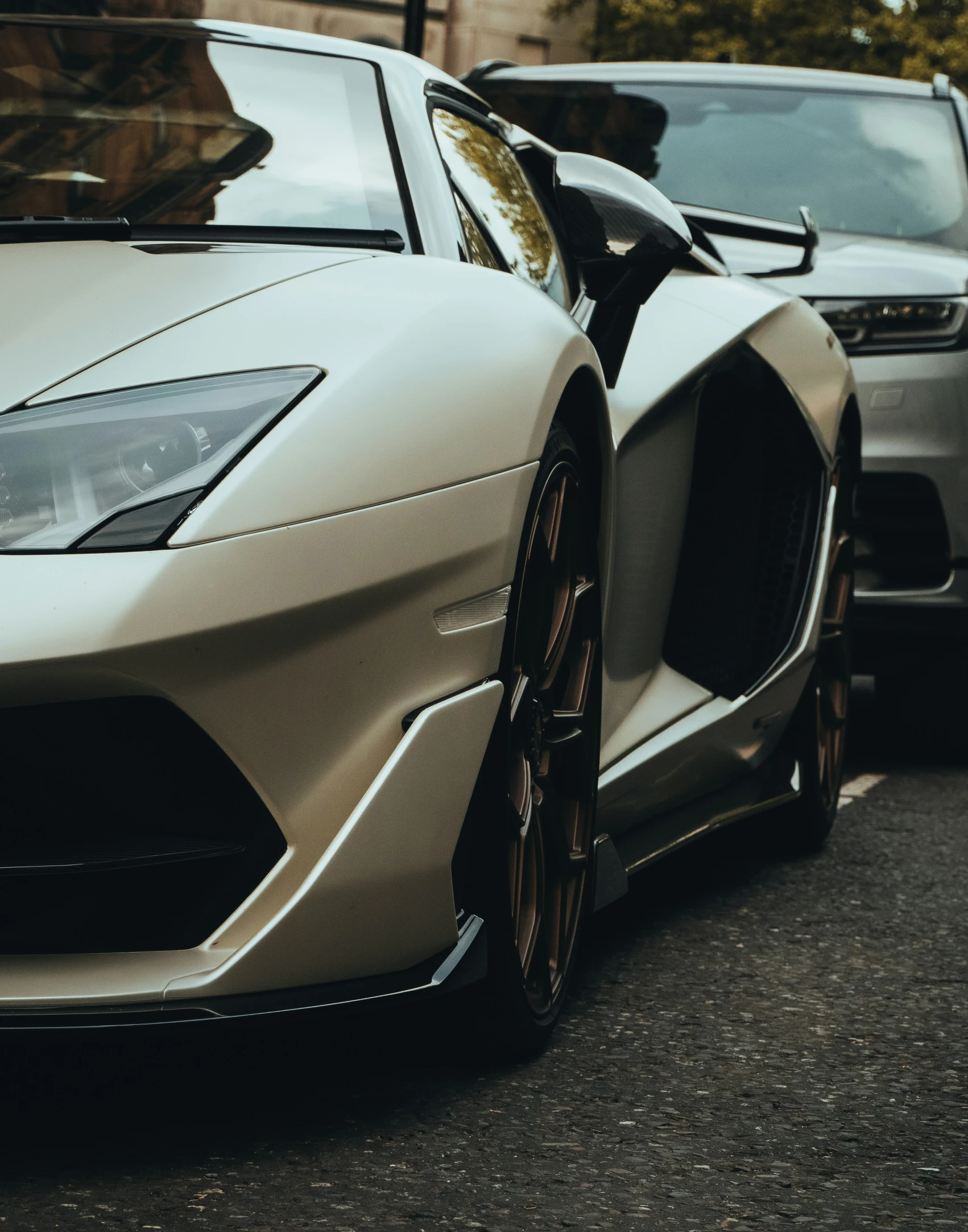 two sport cars parked on the street one has its door open