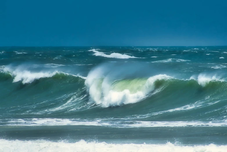 a bunch of green ocean waves rolling into shore