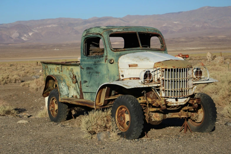 an old rusty green truck sits in the desert