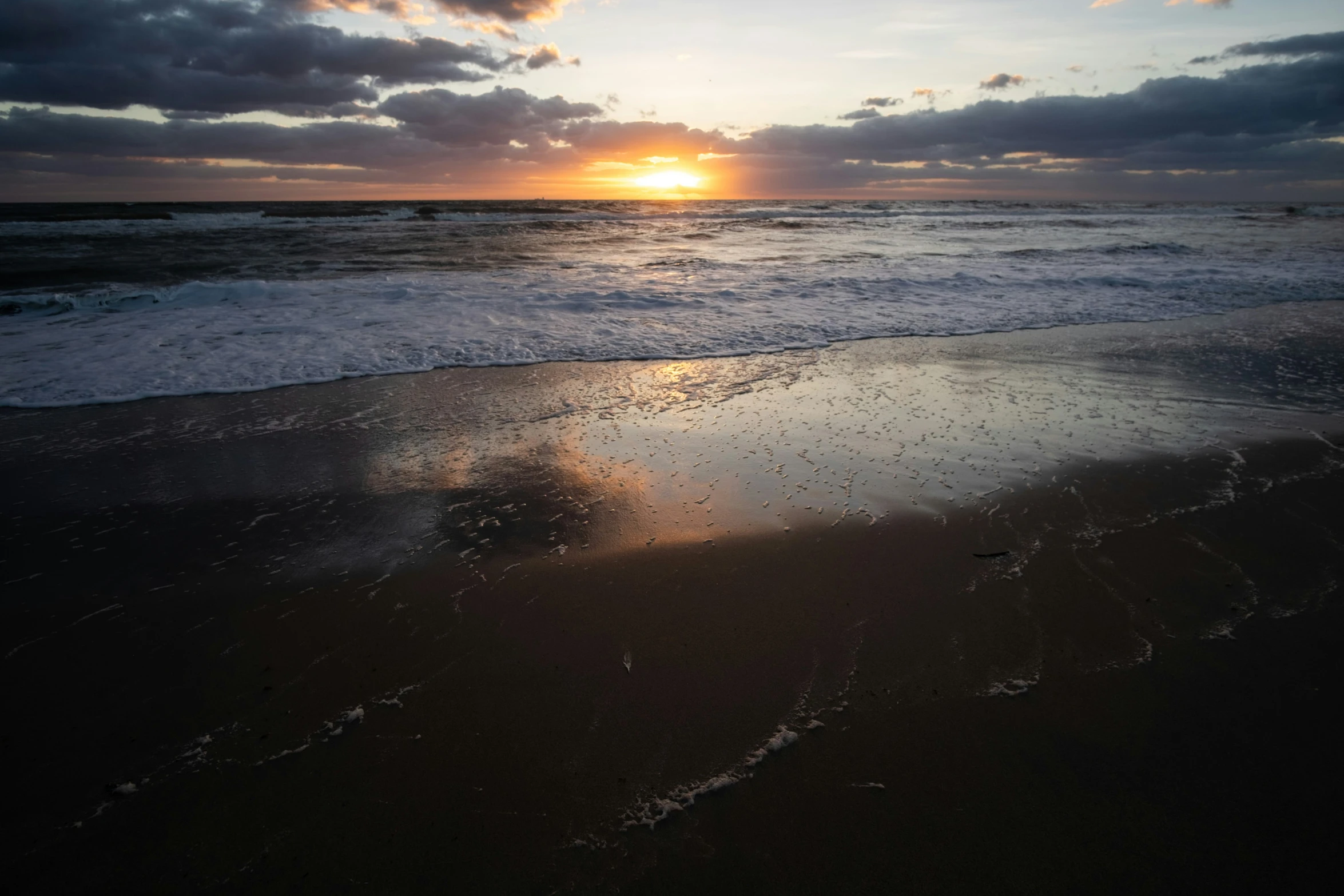 the sun setting in the clouds over a beach