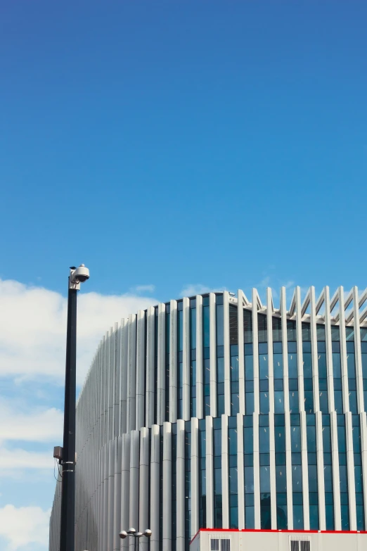 the tall street lamp stands beside a circular building