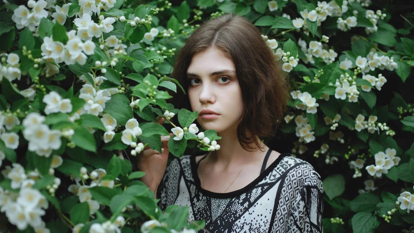 a young woman is standing among flowers