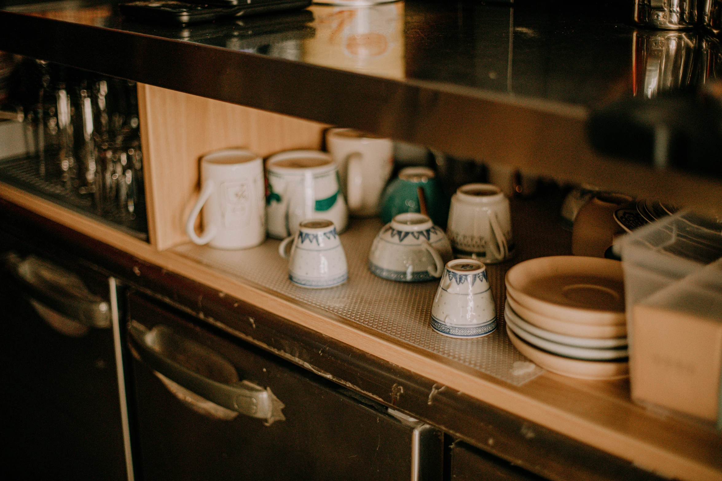 there are several ceramic cups and bowls that are sitting on the shelf