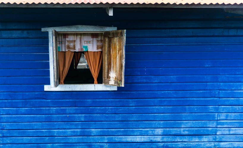 a blue wall with a window with a curtain