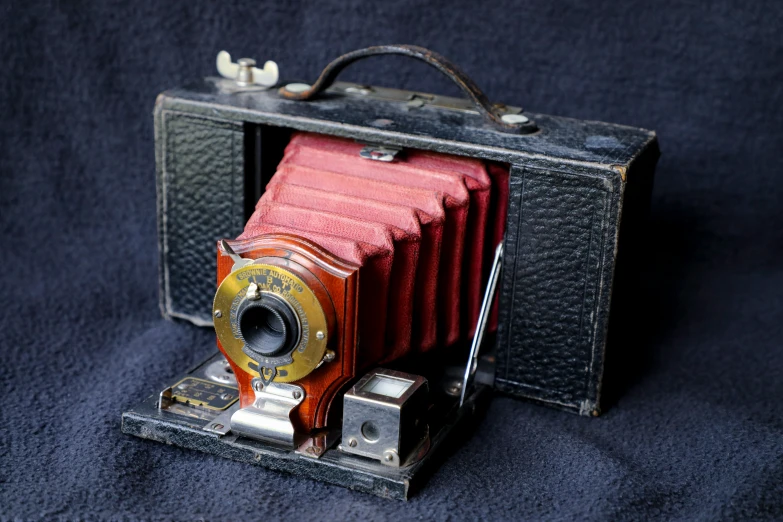 an old fashioned camera on a dark surface