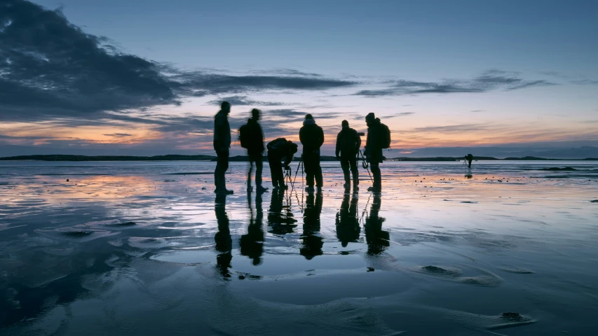 the group of people are standing on a beach