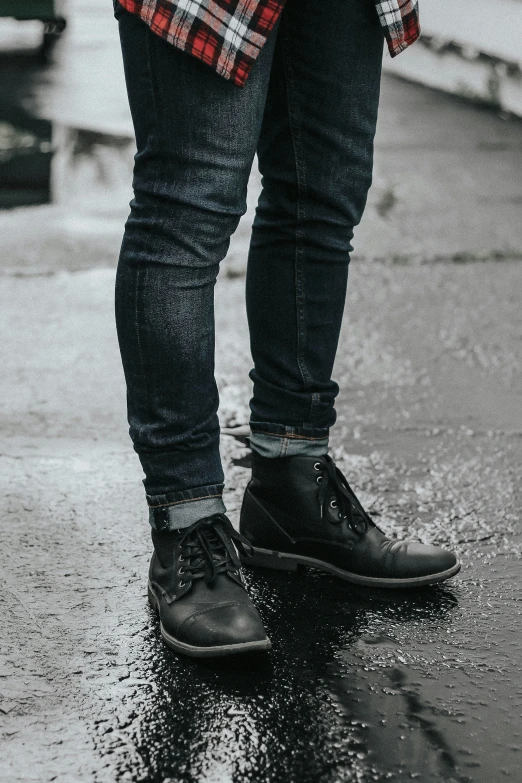 a person standing on wet pavement in front of a parking lot