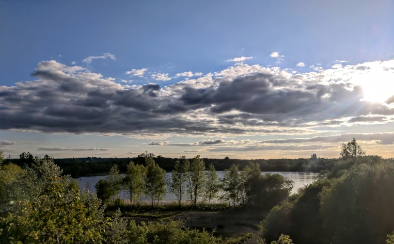 the sun shines on trees on a partly cloudy day