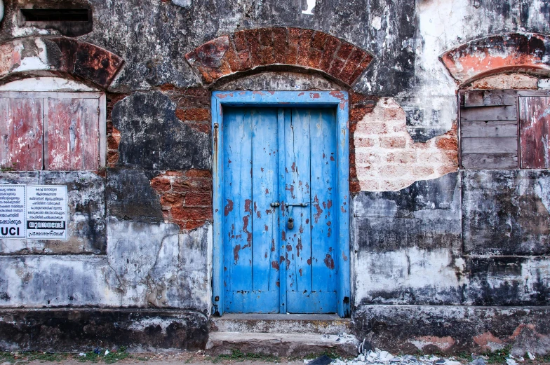 an old wall has two windows and an door