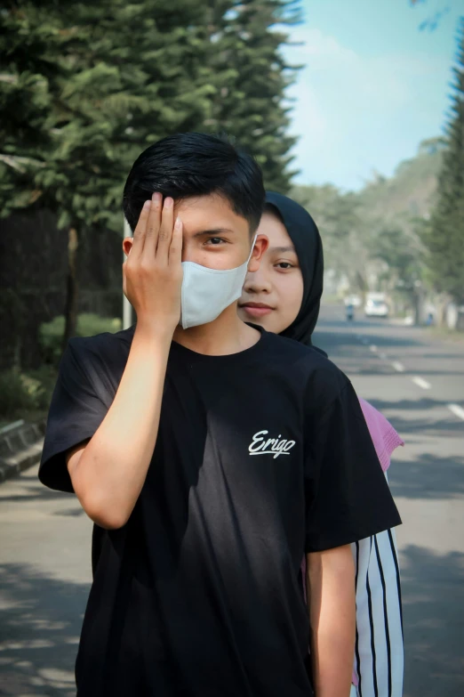 a couple wearing face masks stand on the side walk