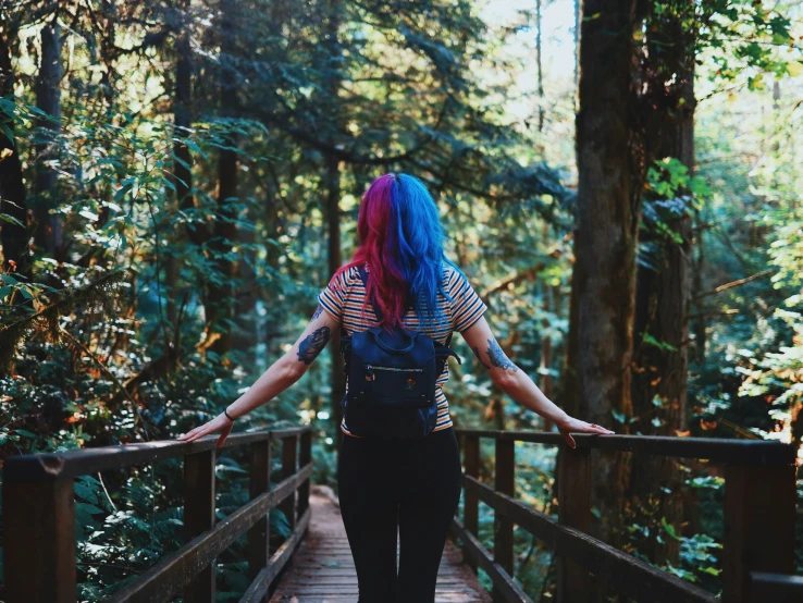 a woman walking down a walkway in the woods