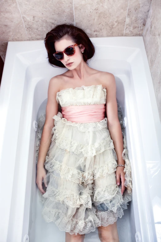 a woman in a bath tub wearing sunglasses