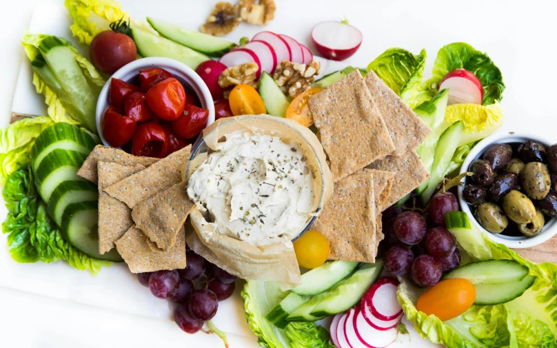 a plate full of salad, ers, gs, cherries and nuts