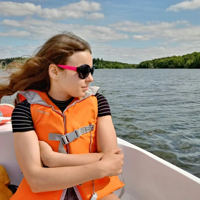 a girl in sunglasses and life vest paddling the boat